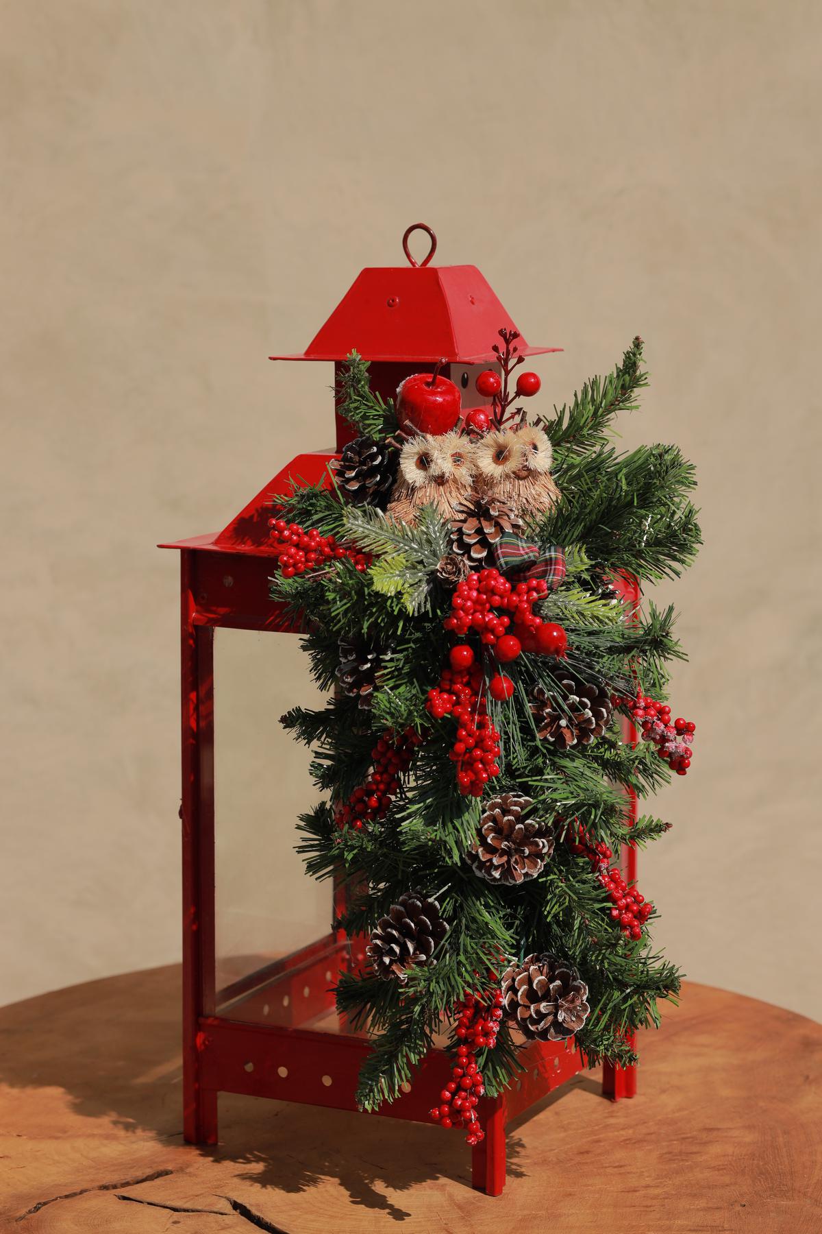 Metal lanterns adorned with pine cones and faux flowers at Wudapple