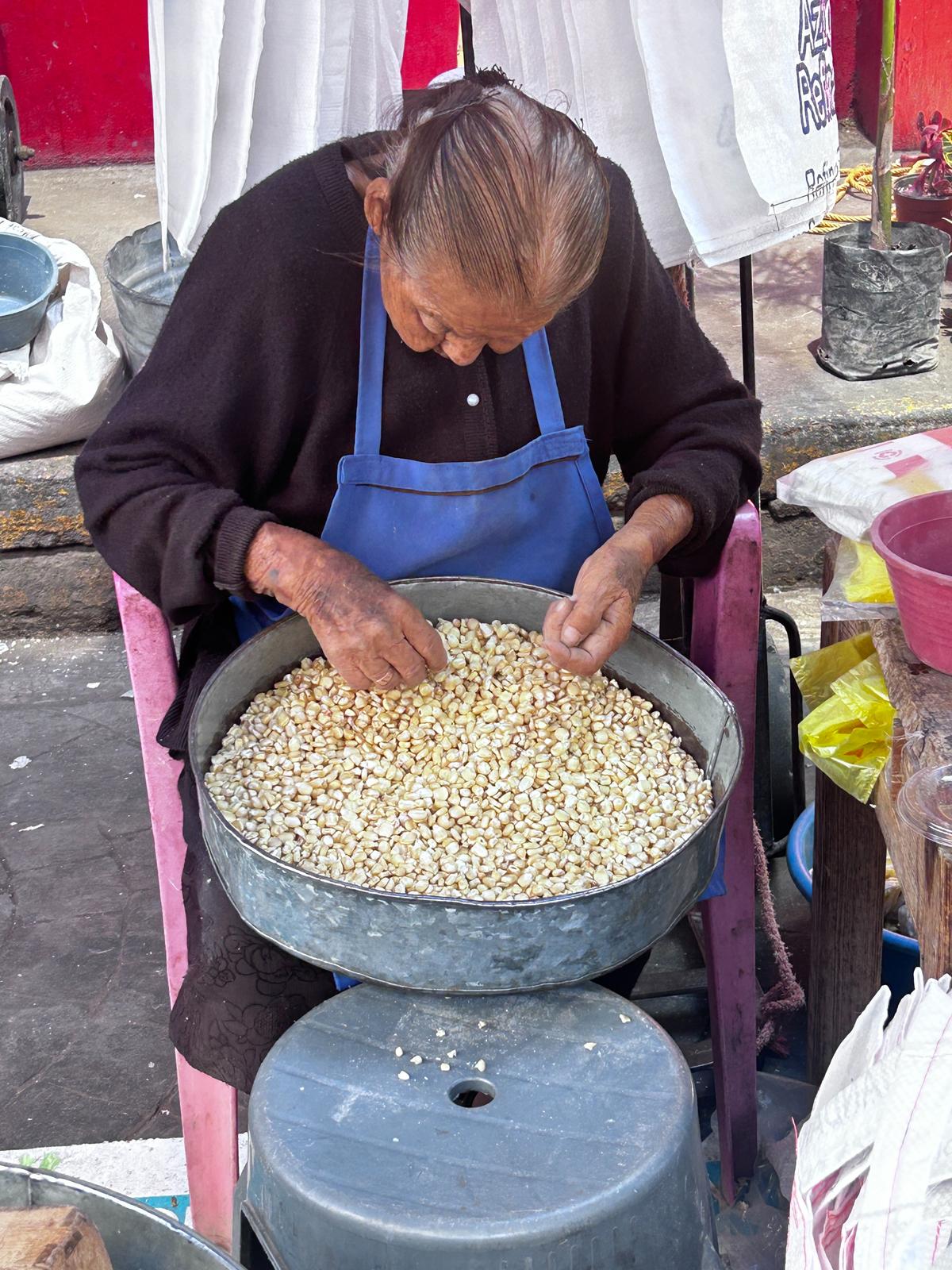 A vendor picking dried corn at Tlacolula Market in Oaxaca, Mexico