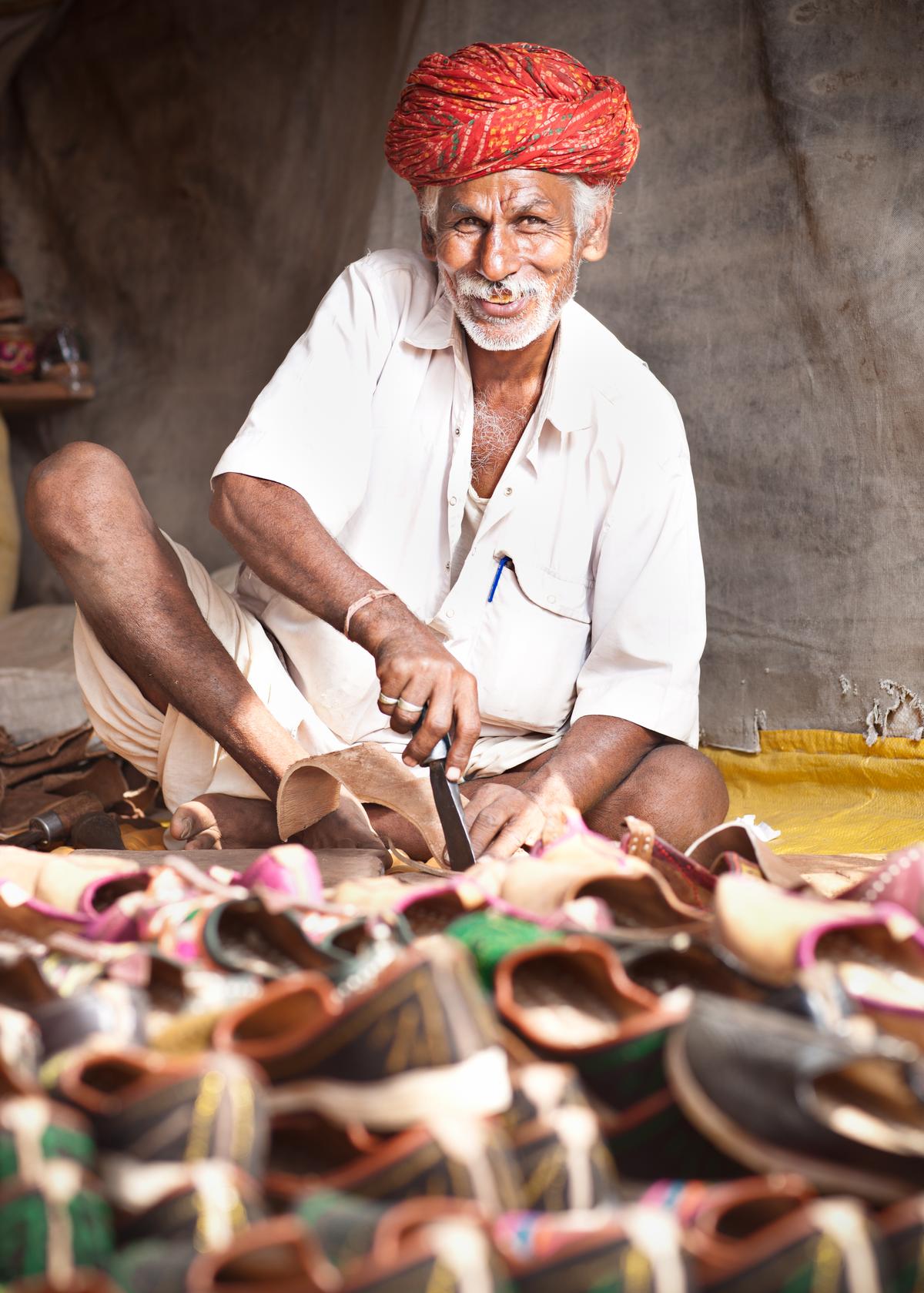 An artisan crafting footwear at Pushkar. An artisan crafting footwear at Pushkar.