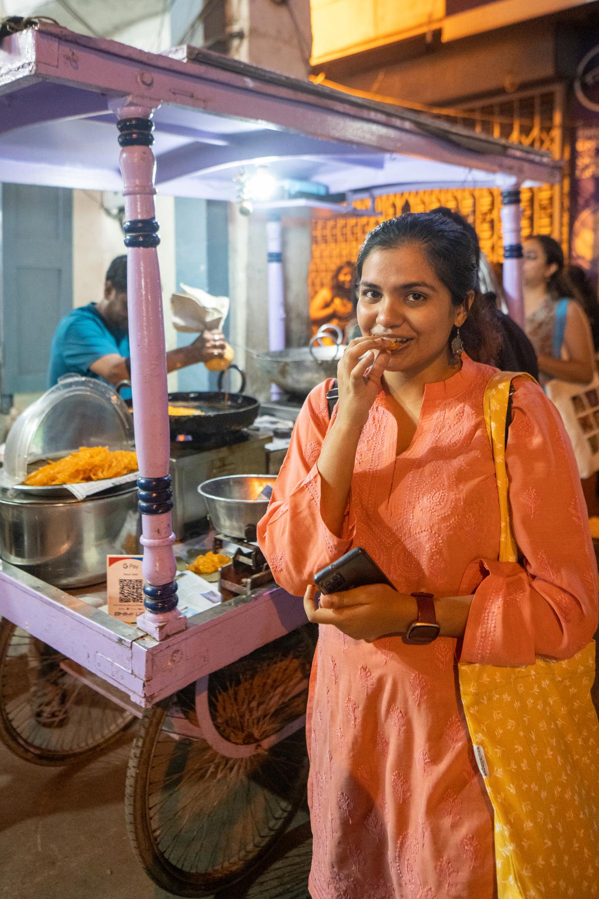 Tulika Bhattacharya, a 24-year-old consultant from the city, savors hot jalebis from a street cart in Chickpet during a walk.