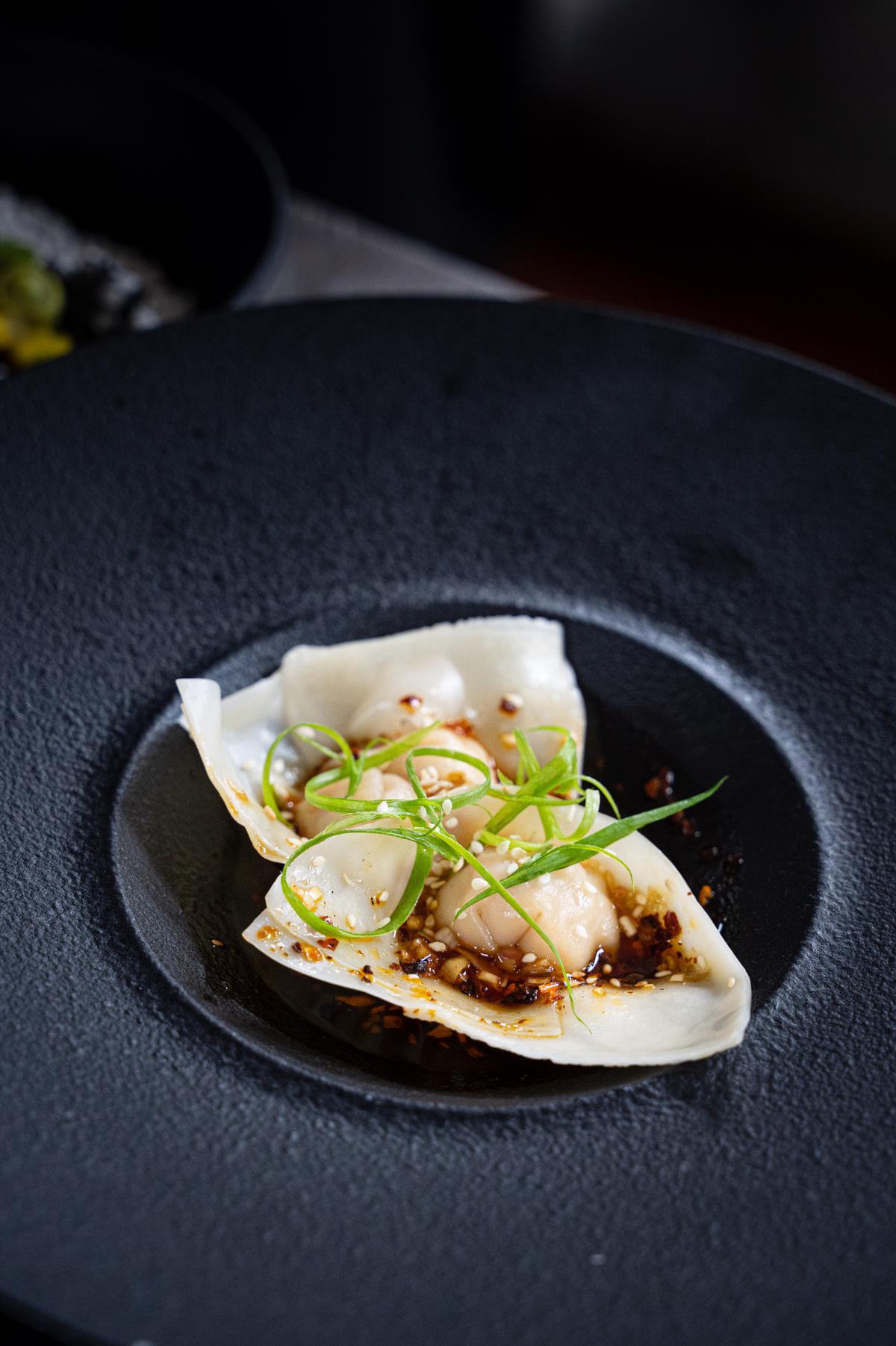 Prawn wontons with black vinegar and tamari dressing, Sichuan chilli oil, spring onion and toasted white sesame seeds