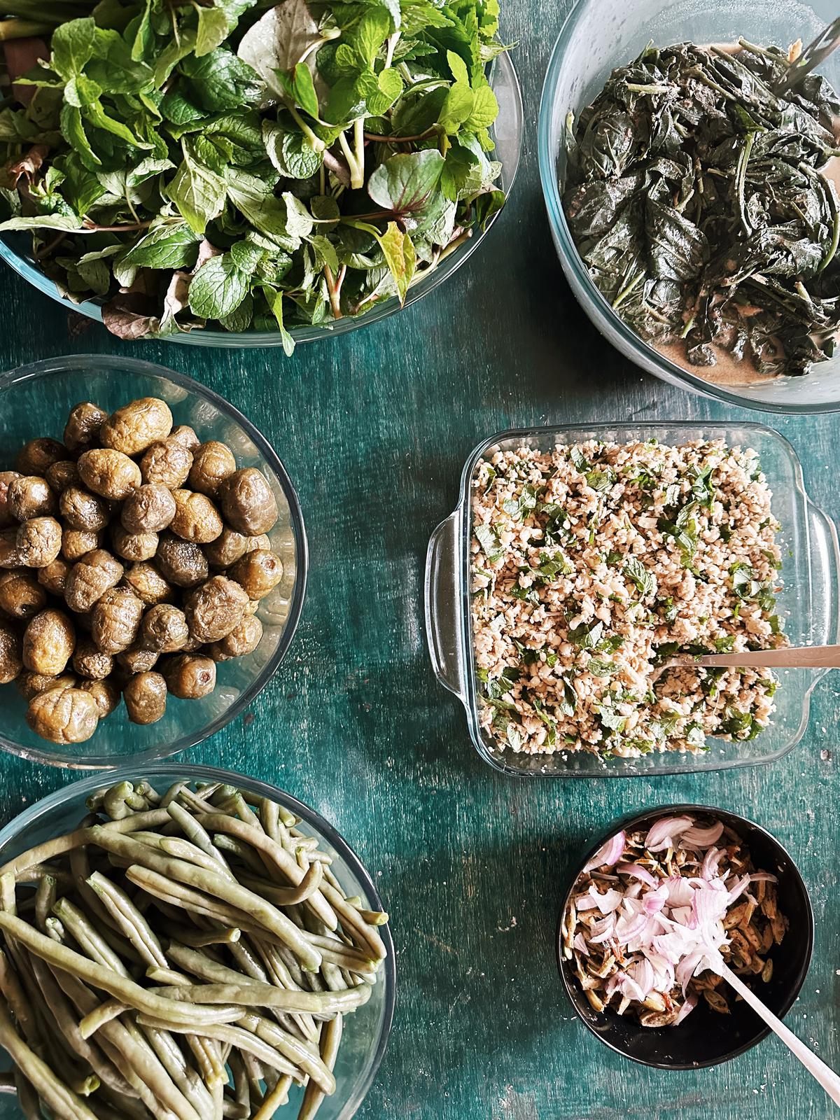 (Clockwise) Foraged leaves - fish mint, pennywort and mint, and fiddle fig ferns with perilla powder, white naga beans salad with raw ginger and lungrihan, stinky beans salad with Naga king chilli, green beans steamed and wild olive fermented