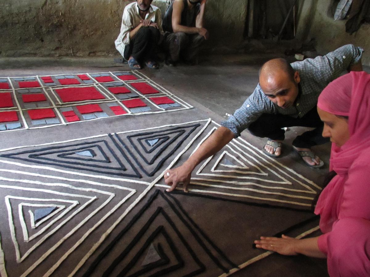 An artisan laying out strips of felt to start a namda rug                