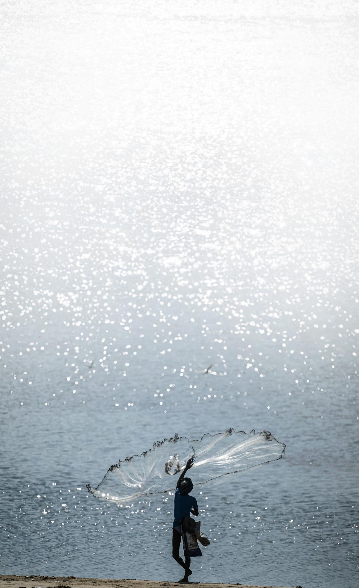 A fisherman casts his net at Srinivasapuram beach in Chennai