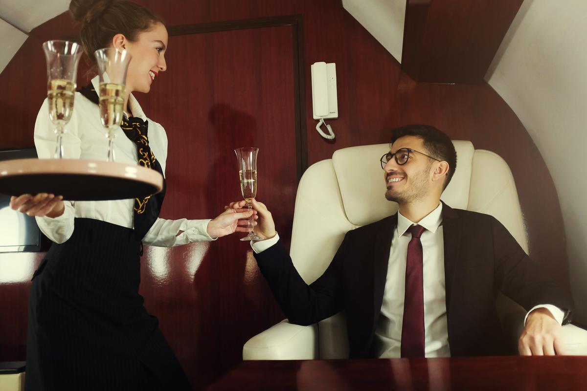 Stewardess brings a glass of champagne on board