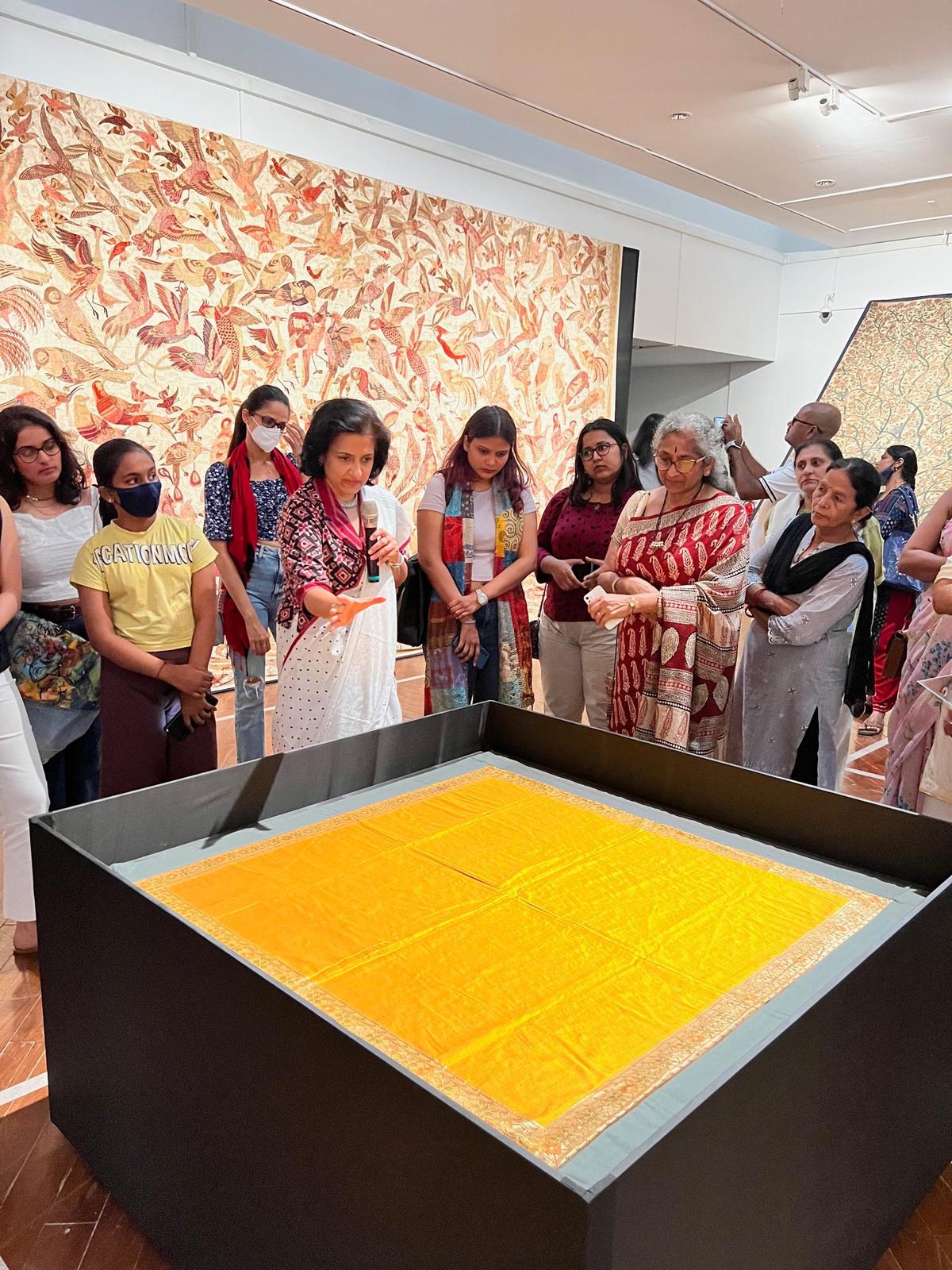 Susan Thomas (in the white sari) with the bird tapestry and the pitambari yellow paithani