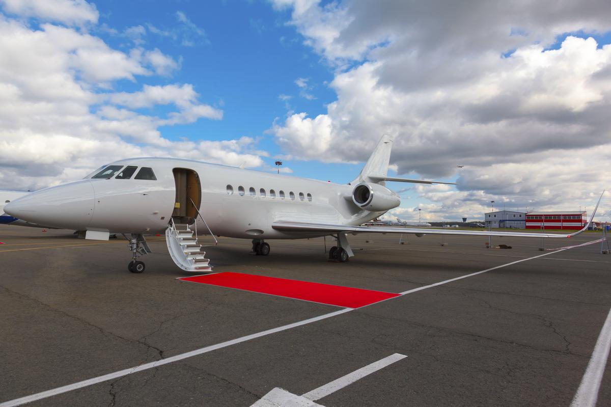 White reactive private jet, the front landing gear and a ladder on blue sky and clouds