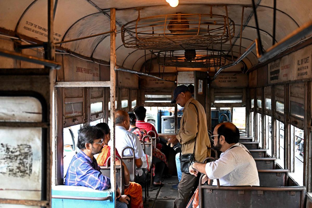 A conductor collects tickets as passengers commute in a tram in Kolkata