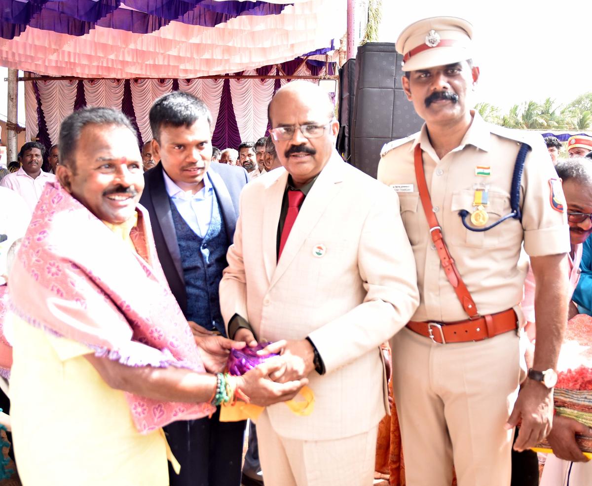 Collector M. Thangavel presenting shawl to a heir of a freedom fighter at the Independence Day celebrations held in Karur on Friday. 