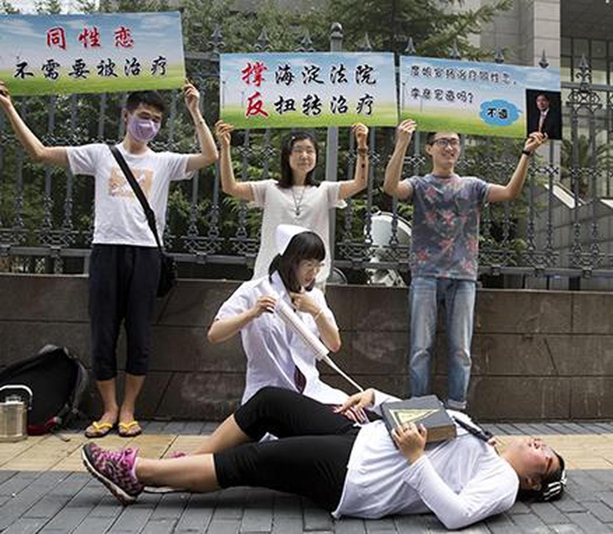 In this July 31, 2014 file photo, gay rights campaigners act out electric shock treatment to protest outside a court when the first court case in China involving so-called conversion therapy is held in Beijing, China. A gay man in central China has successfully sued a mental hospital over forced conversion therapy on June 26, 2017, in what activists are hailing as the first such victory in the country where the LGBT rights movement is gradually emerging form the fringes. 
