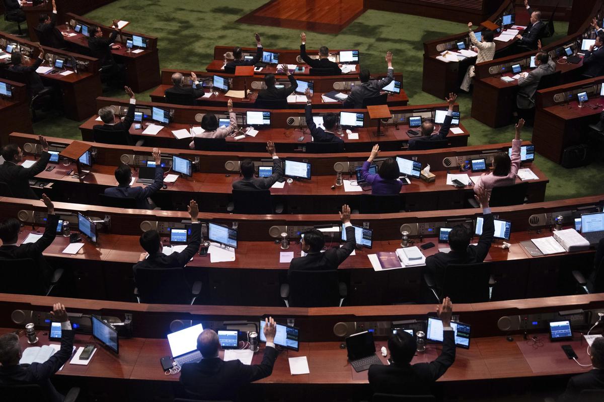 Lawmakers raise their hands to vote after the second reading of the Basic Law Article 23 legislation at the Legislative Council in Hong Kong, March 19, 2024. 