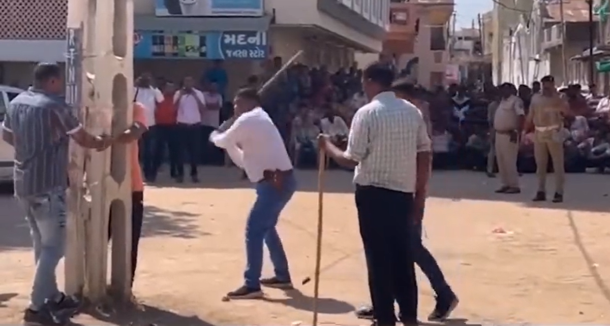 Policemen and crowds watch on as a man is flogged in Kheda