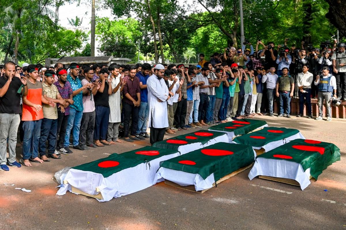 Students protesting against quotas in government jobs offer prayers over symbolic coffins of victims, a day after they died in a clash with police personnel, during an absentee funeral prayer ceremony at Dhaka University in the capital on July 17, 2024. 