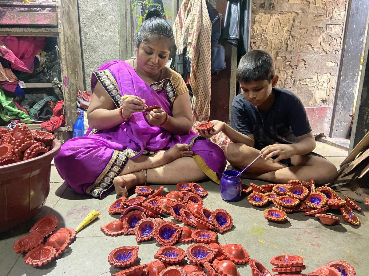 Ten-year-old Kuldeep lends a hand as his mother Meera Gotil decorates lamps.