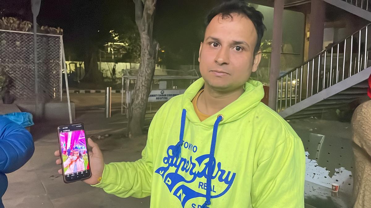 Omi Singh holding photograph of daughter Ayu Singh (deceased) in the New Delhi railway station stampede.