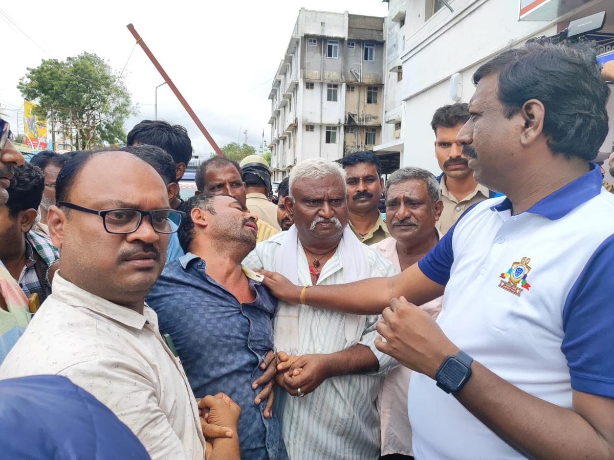 Deputy Commissioner Vijaymahanthesh Danammanavar consoling the father of the deceased boy, who was washed away in an overflowing drain, in Haveri on October 17, 2024. 