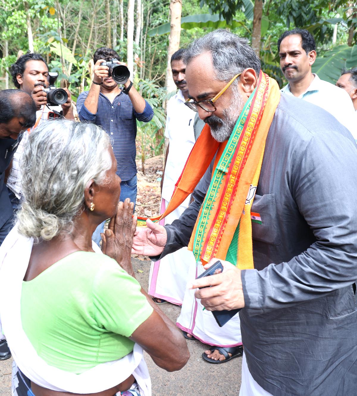 NDA candidate Rajeev Chandrasekhar greets a resident of the Pazhinjippara colony in Aryancode, near Parassala. 