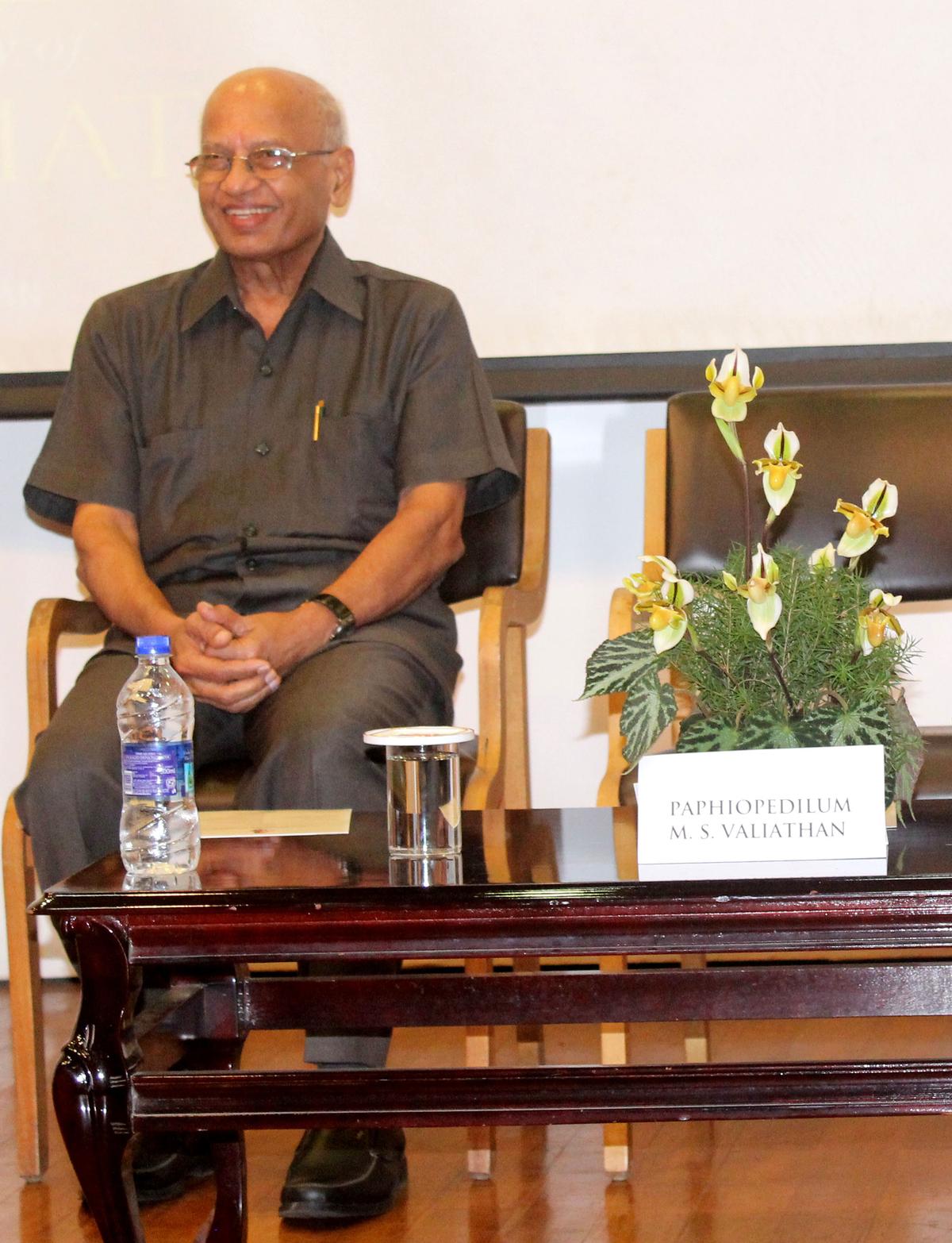 Dr. M. S. Valiathan seated beside the orchid Paphiopedilum M. S. Valiathan: