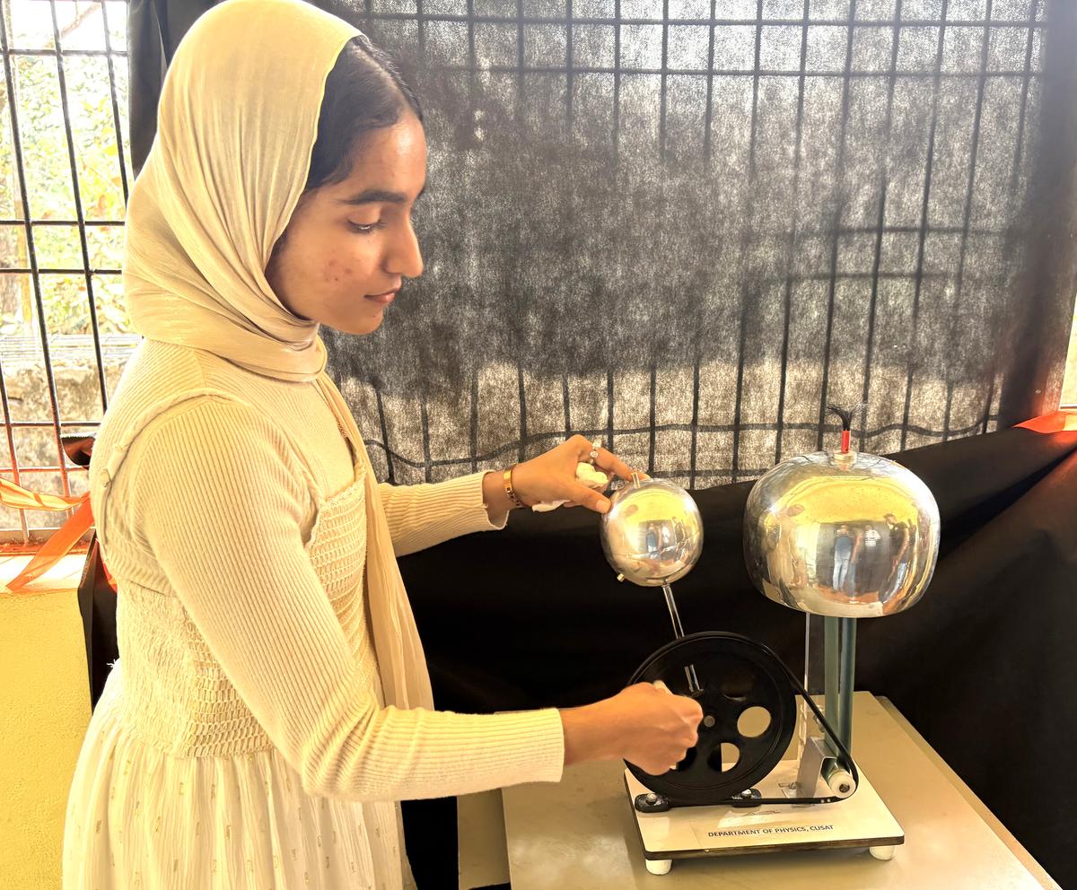 एक छात्र यह दर्शाता है कि हवा को कंडक्टर में बदलकर बिजली कैसे चमकती है।