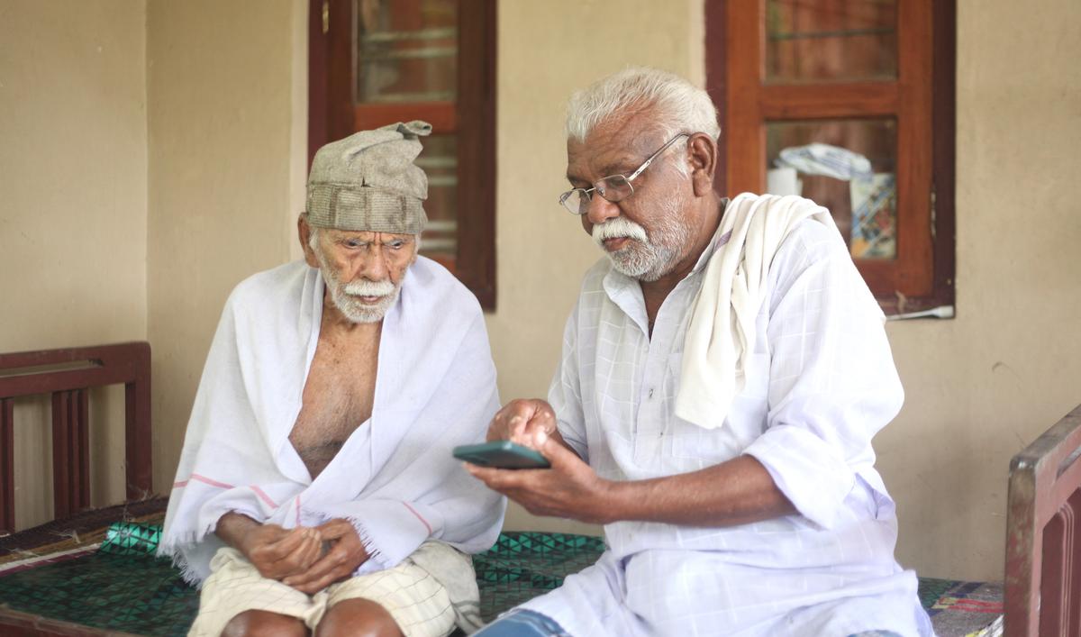 103-year old Karunaka Panicker and his son, Rajan, watching a song on YouTube at their home in Pullampara panchayat in Thiruvananthapuram.