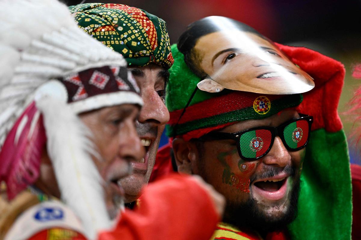 Portugal supporters, one with a mask of Portugal’s forward #07 Cristiano Ronaldo on his head, cheer ahead of the Qatar 2022 World Cup Group H football match between Portugal and Ghana at Stadium 974 in Doha on November 24, 2022. 