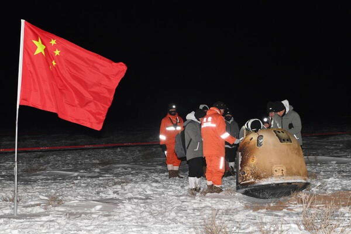 Researchers work around Chang'e-5 lunar return capsule carrying moon samples next to a Chinese national flag, after it landed in northern China's Inner Mongolia Autonomous Region, December 17, 2020. 