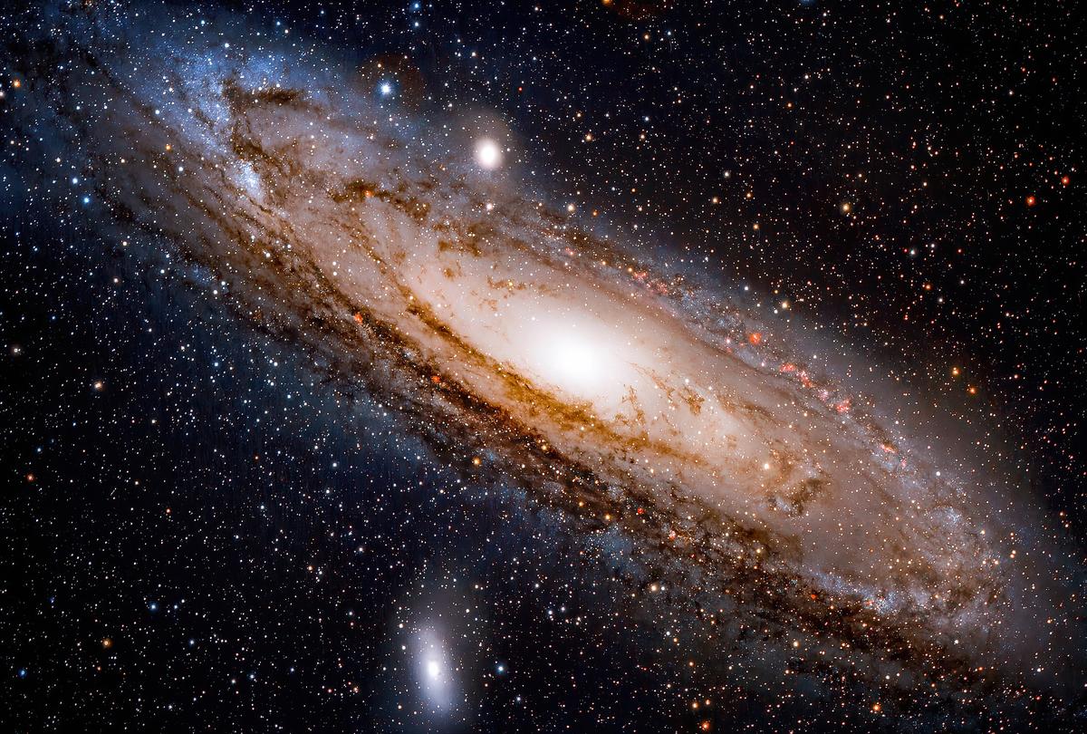 The Andromeda Galaxy (Messier 31) seen through a telescope and enhanced to highlight certain features. The small Messier 32 galaxy is seen above and slightly to the left (directly south) of the centre of M31, and Messier 110 is below and to the left.