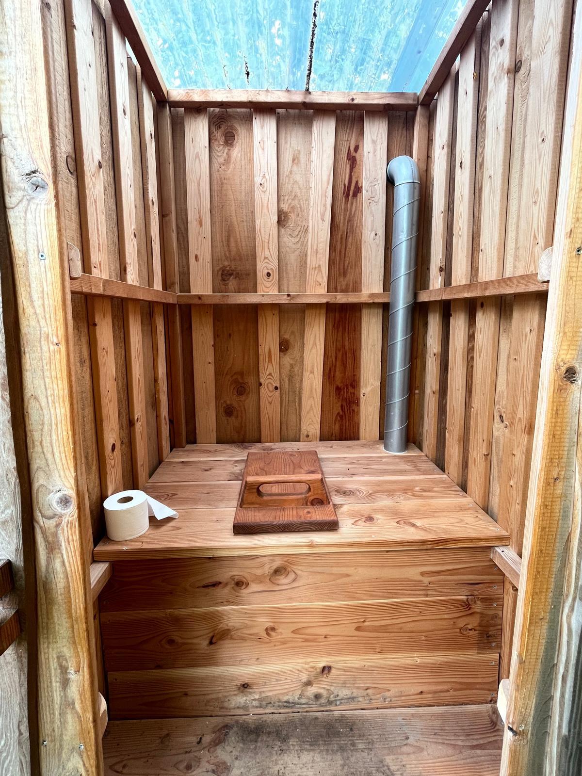 Interior view of a minimalistic dry pit toilet made of natural wood, Norway.