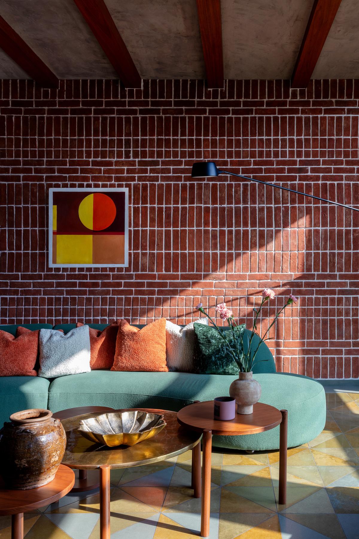 A rhythmic terracotta brick wall with bold white lime grouting creates a striking backdrop for this vibrant seating space. 