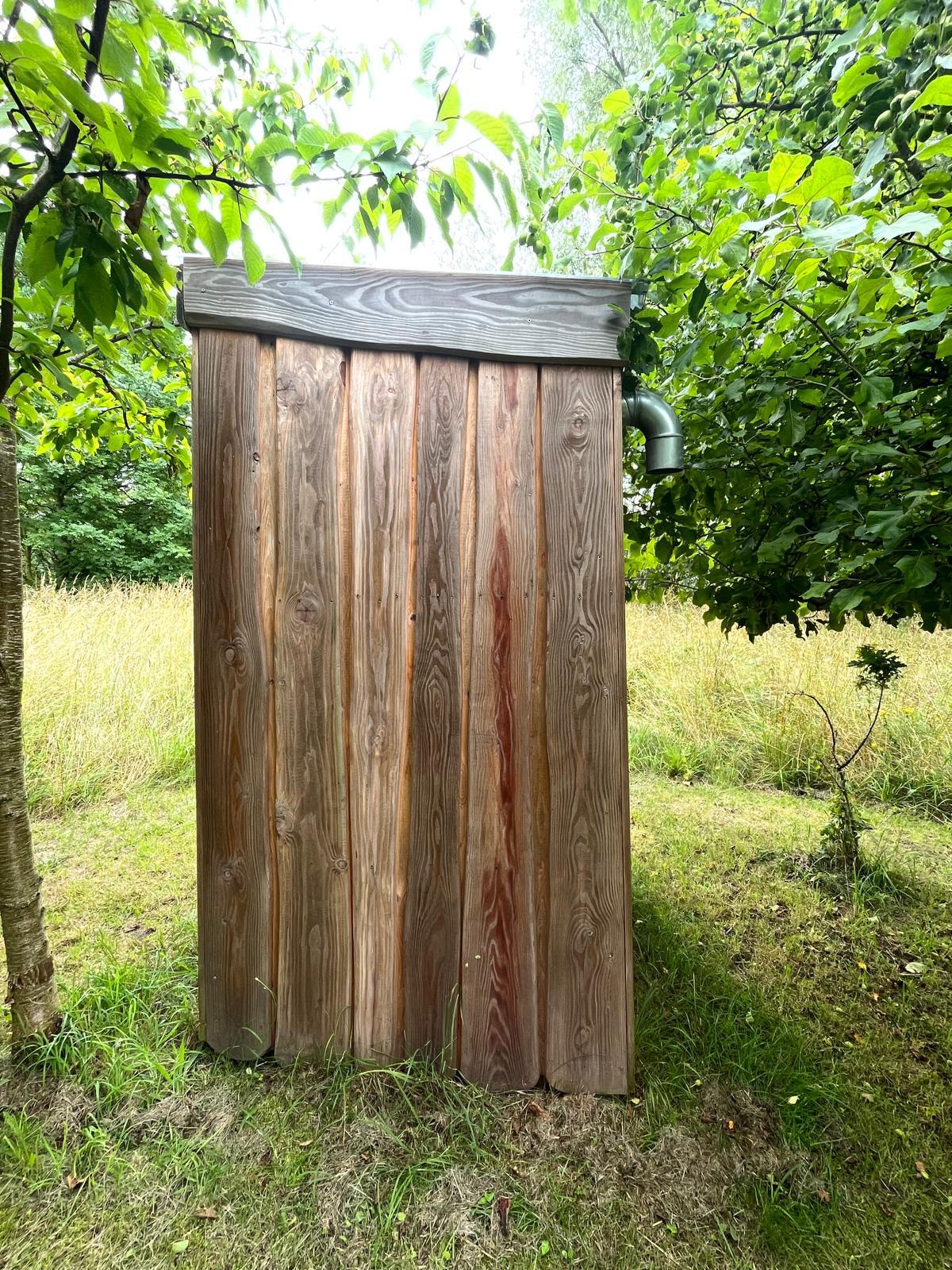 Outside view of log cabin of long drop toilet in the woods, Norway.