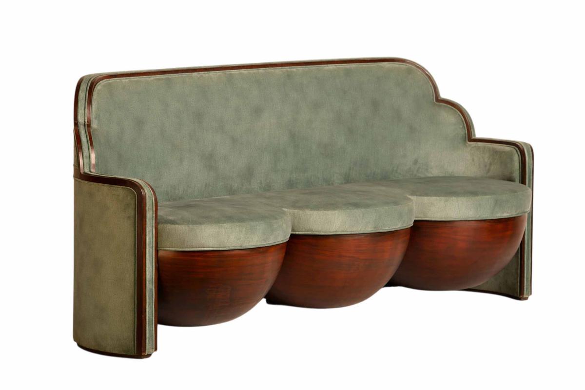 A sculptural sofa with rounded base and upholstered seating. A sculptural sofa with rounded base and upholstered seating.