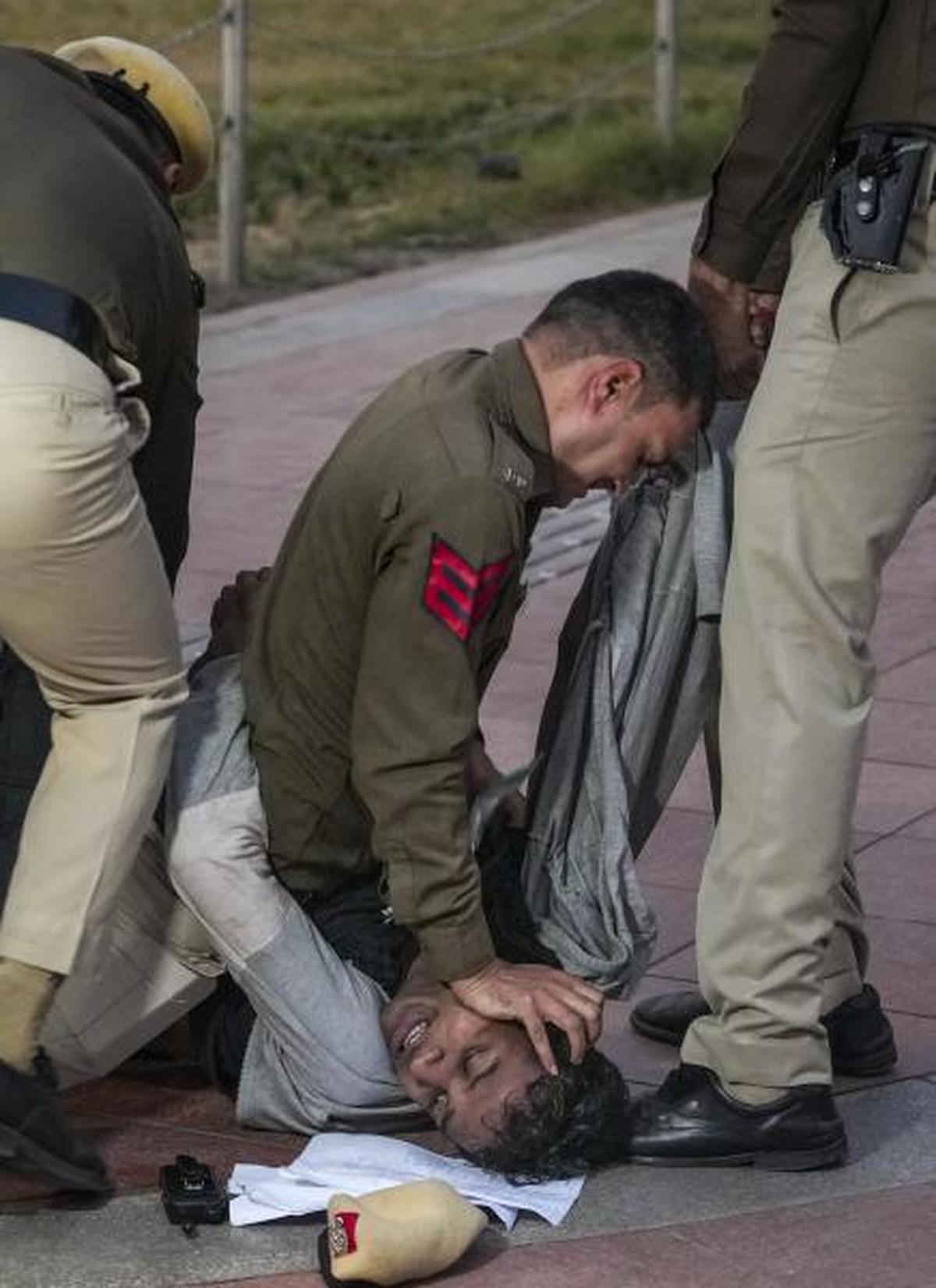 Police personnel detain a protestor during a protest against Delhi air pollution. Police personnel detain a protestor during a protest against Delhi air pollution.