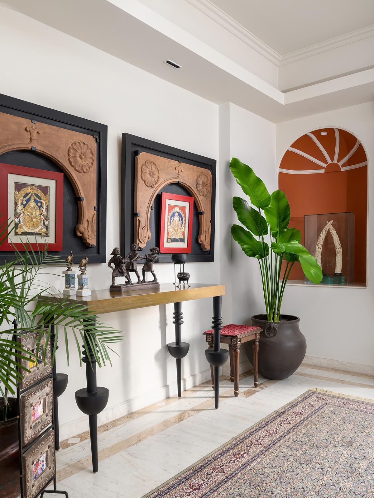 In the foyer, heirloom frames adorned with floral carvings meet a Mughal-inspired arch niche, adding an elegant prelude to the home’s classical narrative. In the foyer, heirloom frames adorned with floral carvings meet a Mughal-inspired arch niche, adding an elegant prelude to the home’s classical narrative.