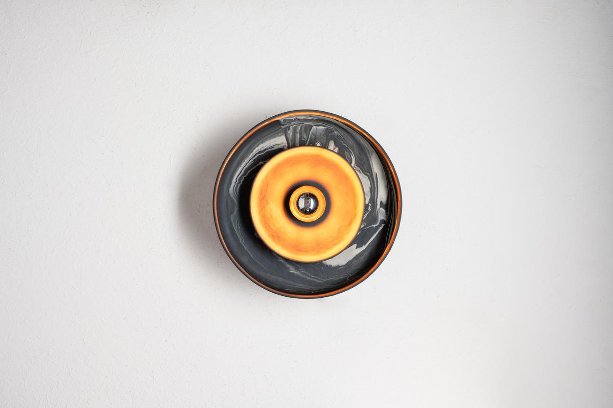 A variety of the Terra Wall Sconce that merges deep greys with warm hues. A variety of the Terra Wall Sconce that merges deep greys with warm hues.