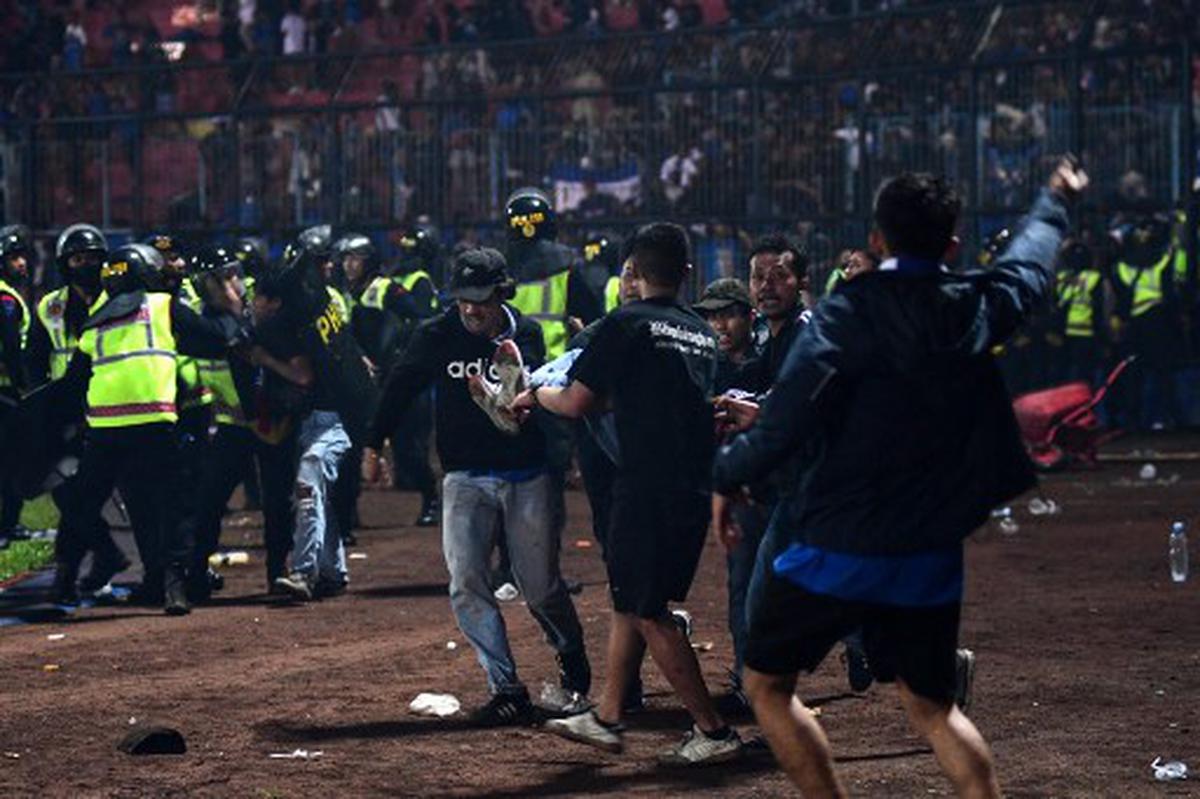 Un groupe de personnes transporte un homme après que des affrontements ont éclaté lors d'un match de football entre Arema FC et Persebaya Surabaya au stade Kanjuruhan à Malang, Java oriental, Indonésie, le 1er octobre 2022. 