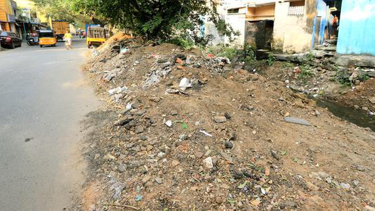 On Puliyur Main Road, debris is placed by the side of Trustpuram Canal