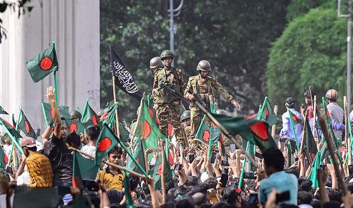 Protesters march to PM Sheikh Hasina’s palace as army personnel stand guard in Dhaka on August 5, 2024. Protesters march to PM Sheikh Hasina’s palace as army personnel stand guard in Dhaka on August 5, 2024.