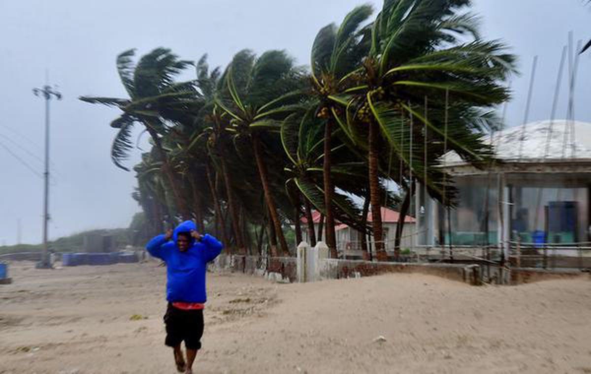 A man runs to safety as high-speed winds due to Cyclone Michaung lashed the Suryalanka beach in Bapatla district, December 5, 2023.